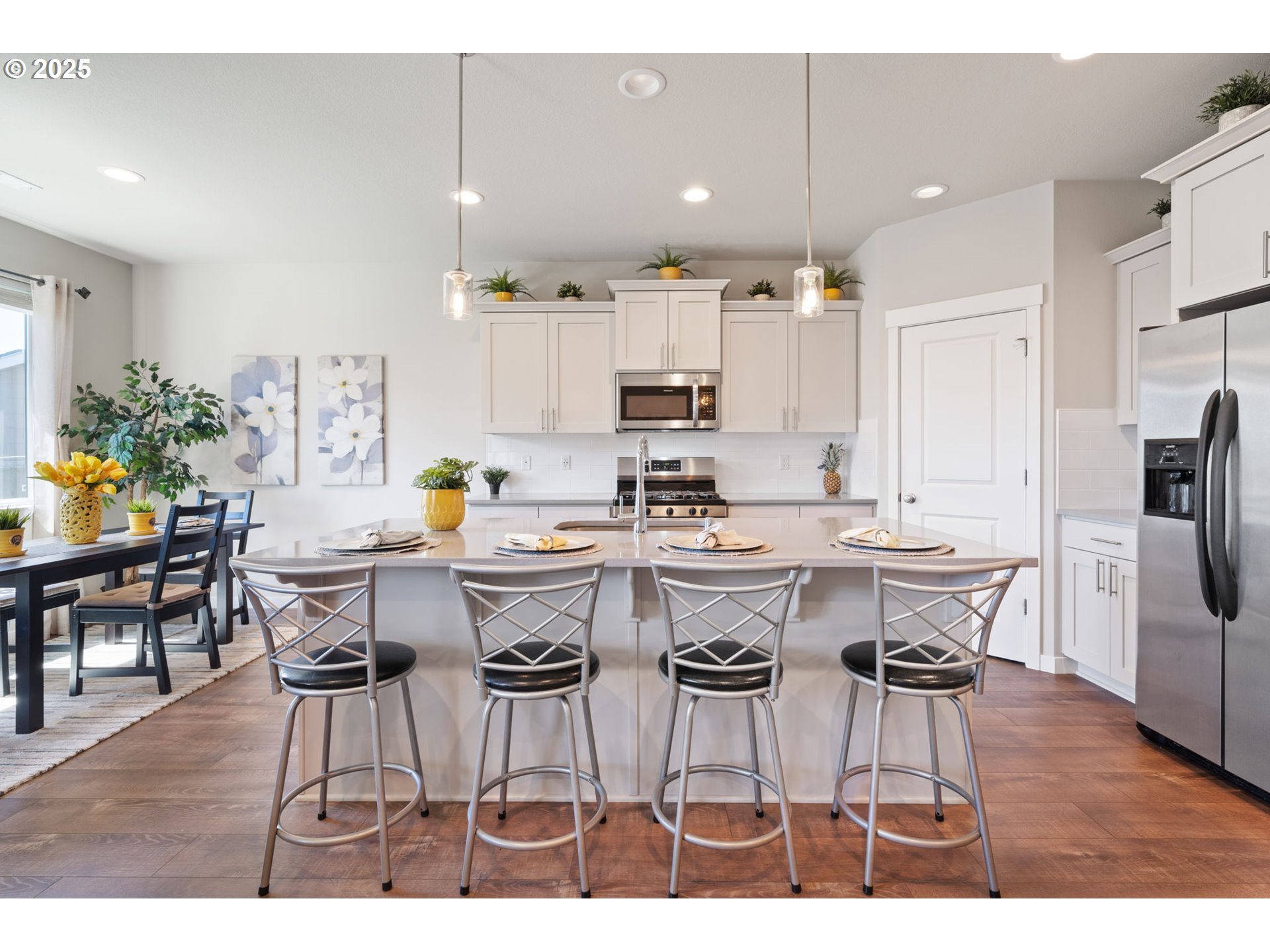 8707 North 1st Street Ridgefield, WA 98642 - Photo 8 of 40 a kitchen with a dining table chairs refrigerator and cabinets