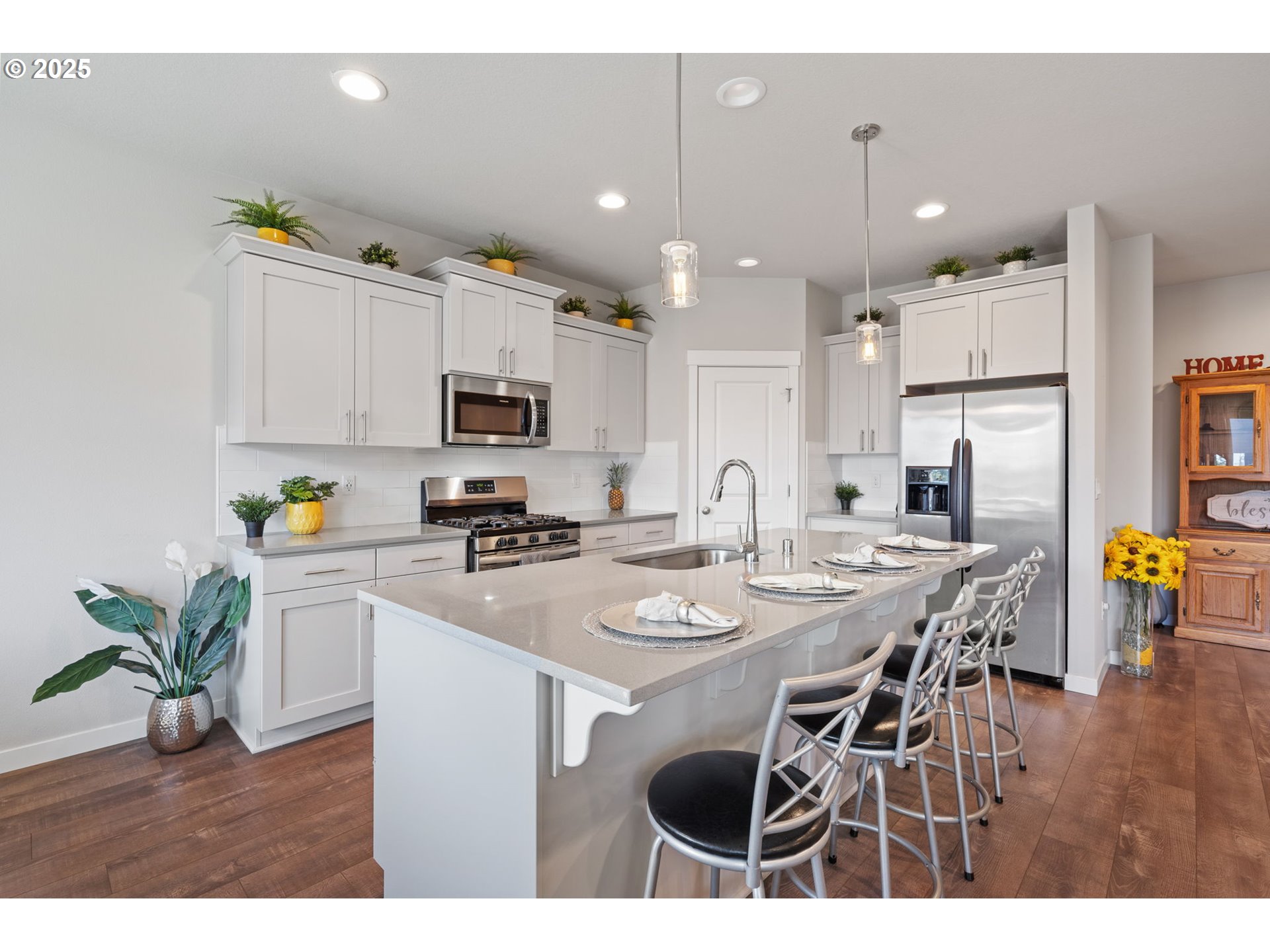 8707 North 1st Street Ridgefield, WA 98642 - Photo 10 of 40 a kitchen with stainless steel appliances kitchen island granite countertop a refrigerator a stove a sink a dining table and chairs with wooden floor