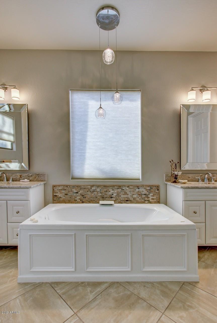 3977 East Hashknife Road Phoenix, AZ 85050 - Photo 20 of 28 a bathroom with a granite countertop sink a mirror and a bathtub