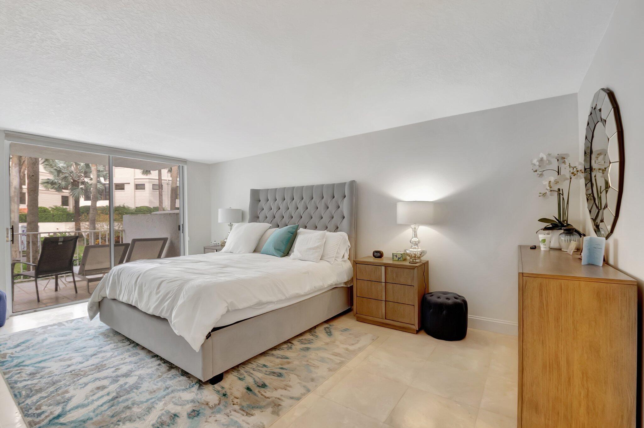 7370 Orangewood Lane, Unit 107 Boca Raton, FL 33433 - Photo 17 of 78 a bedroom with a large bed and a flat tv screen on dresser