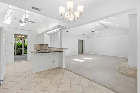 a large white kitchen with granite countertop a sink and cabinets