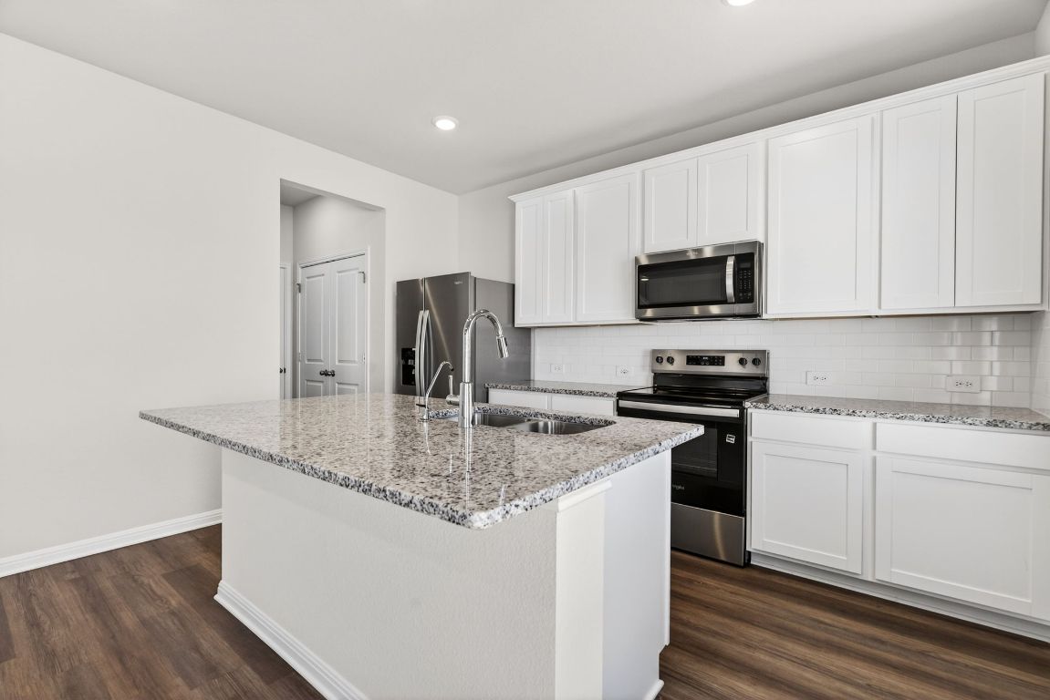145 Honey Bee Road Jarrell, TX 76537 - Photo 7 of 27 a kitchen with stainless steel appliances granite countertop a stove a sink and a refrigerator