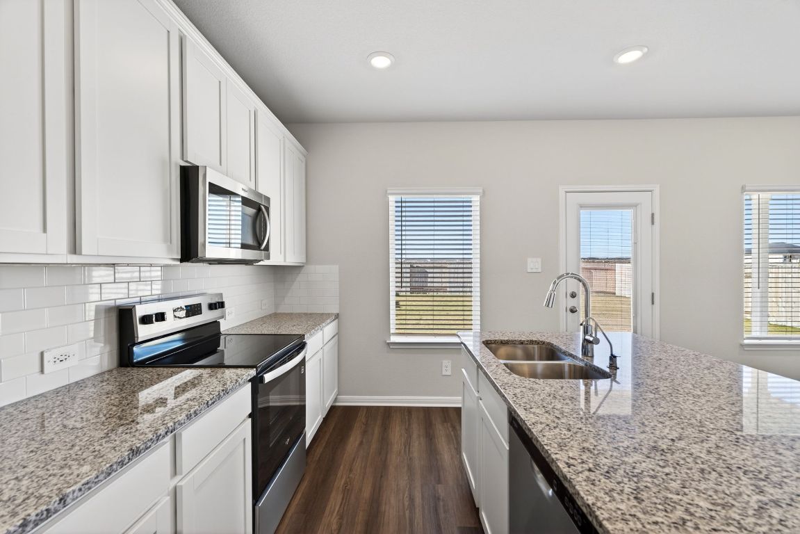 145 Honey Bee Road Jarrell, TX 76537 - Photo 8 of 27 a kitchen with granite countertop kitchen island wooden cabinets granite counter tops and a window