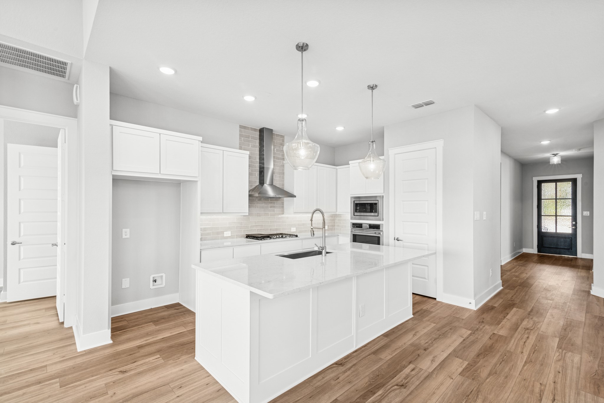 16142 Rita Road Conroe, TX 77302 - Photo 20 of 48 a kitchen with a sink a stove a refrigerator and white cabinets with wooden floor