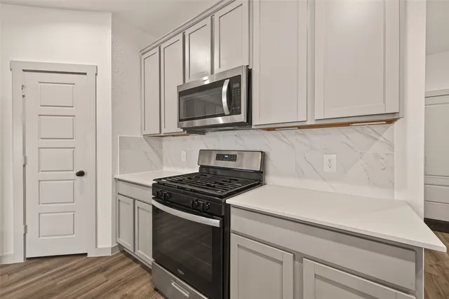 a kitchen with white cabinets stainless steel appliances and wooden floor