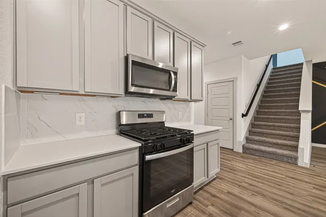 a kitchen with granite countertop cabinets stainless steel appliances and wooden floor