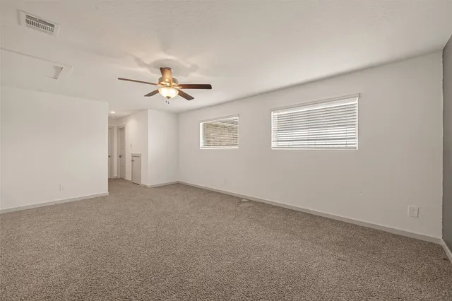 a view of an empty room with a ceiling fan and window