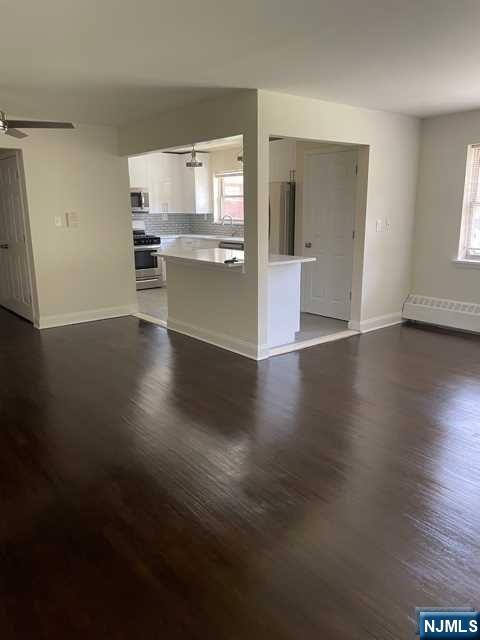 280-320 Oak Street, Unit 290D Ridgewood, NJ 07450 - Photo 3 of 20 an empty room with wooden floor and a kitchen