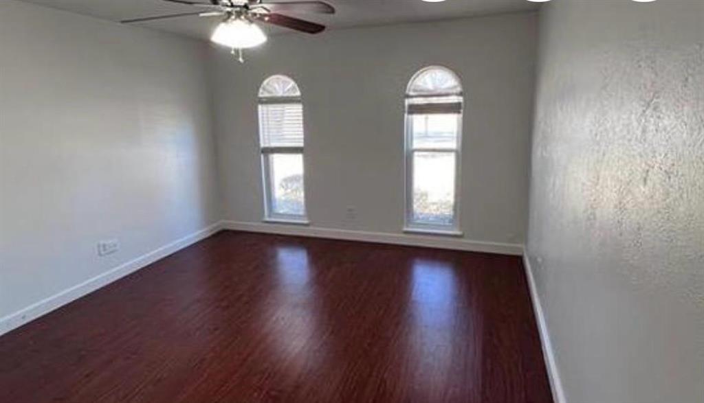 4422 Galaxie Road Garland, TX 75044 - Photo 8 of 11 Room featuring wood-finish flooring, light-toned walls, two arched windows with blinds, and a ceiling fan with integrated lighting