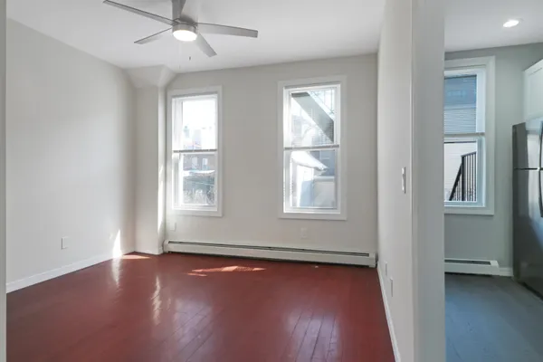an empty room with wooden floor and windows