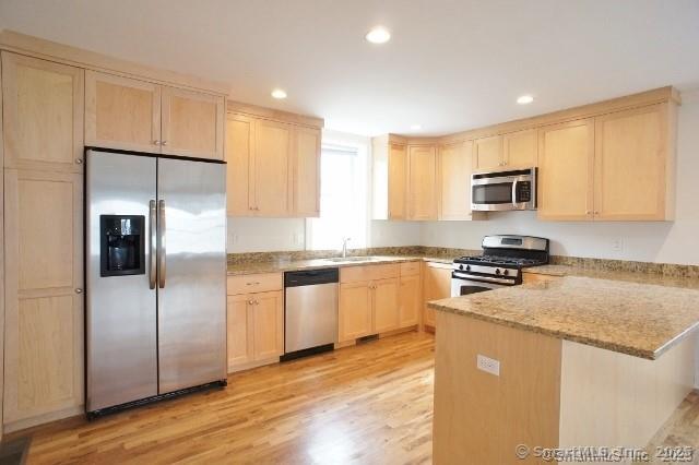 a kitchen with granite countertop a refrigerator a sink a stove a microwave a counter top space and cabinets