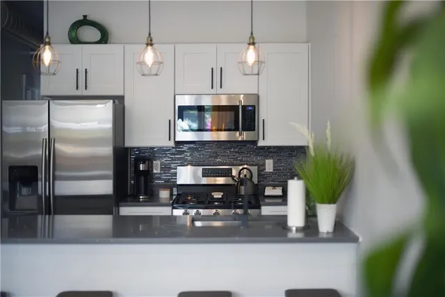 a kitchen with stainless steel appliances granite countertop a refrigerator a stove and a wooden floor