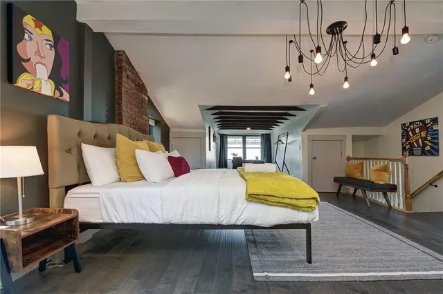 a bedroom with a bed a dresser and potted plants with the wooden floor