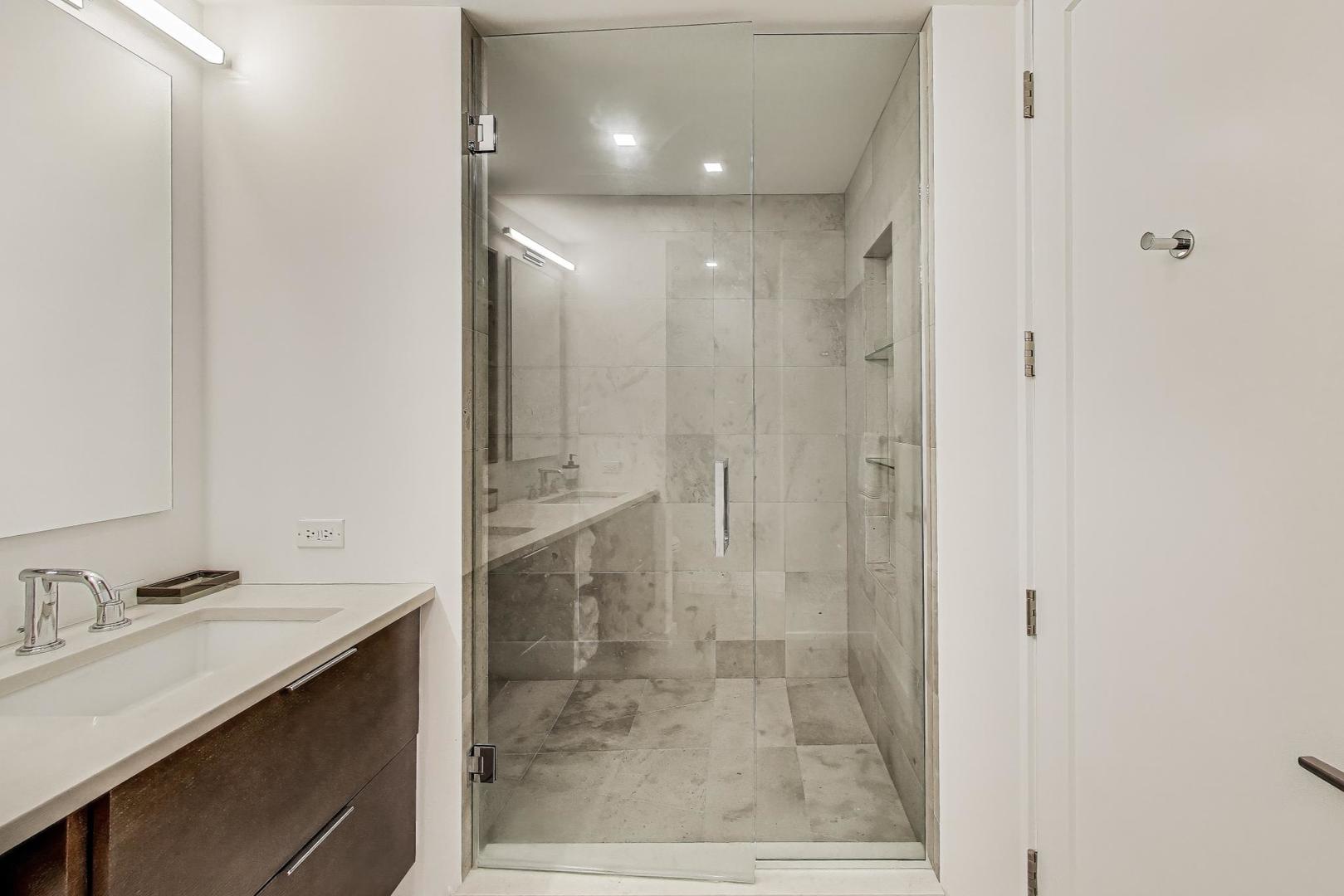 100 East Walton Street, Unit 15DE Chicago, IL 60611 - Photo 14 of 26 a bathroom with a shower sink and mirror