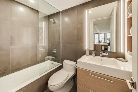 a bathroom with a toilet a sink a mirror a bathtub and shower