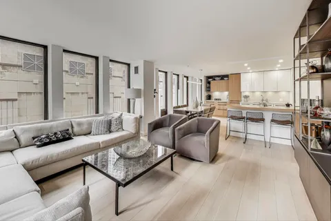 a living room with furniture kitchen view and large windows