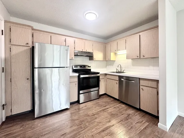 a kitchen with a refrigerator a sink and wooden floor