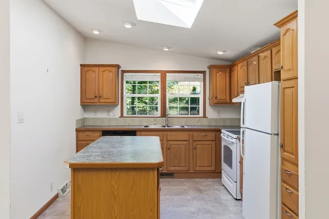 a kitchen with a refrigerator a stove a sink dishwasher and wooden cabinets