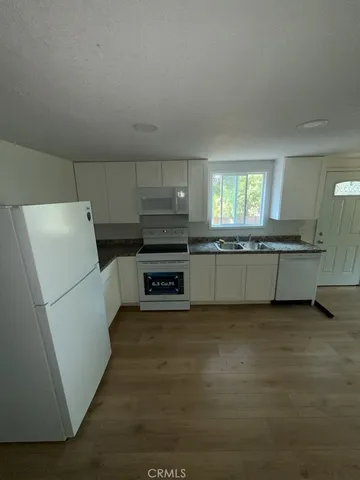 a kitchen with granite countertop a refrigerator and a stove top oven