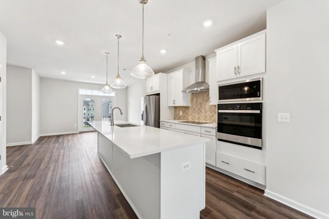 a large kitchen with kitchen island a stove a sink a center island and wooden floor