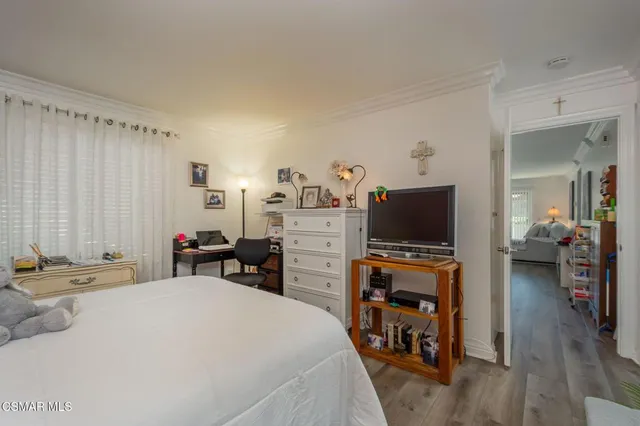 a bedroom with a bed and a flat tv screen on dresser