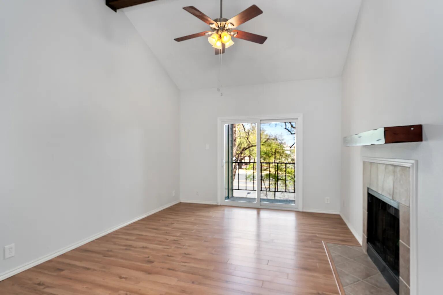 11970 Jollyville Road, Unit 202 Austin, TX 78759 - Photo 3 of 25 A living space offers a fireplace, wood-like flooring, and a private balcony overlooking verdant trees.