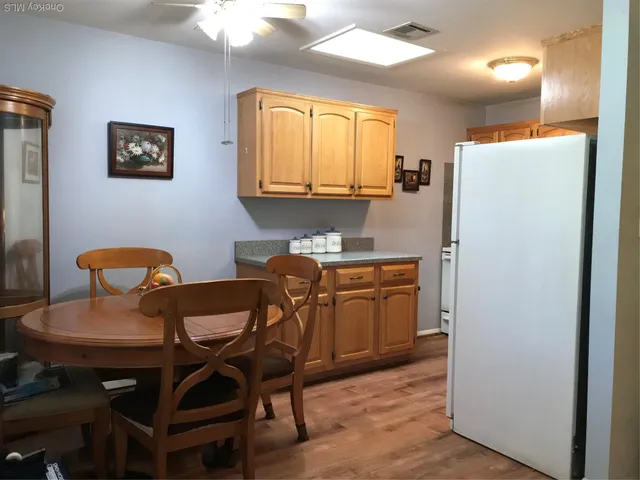 a kitchen with stainless steel appliances granite countertop a dining table chairs refrigerator and sink