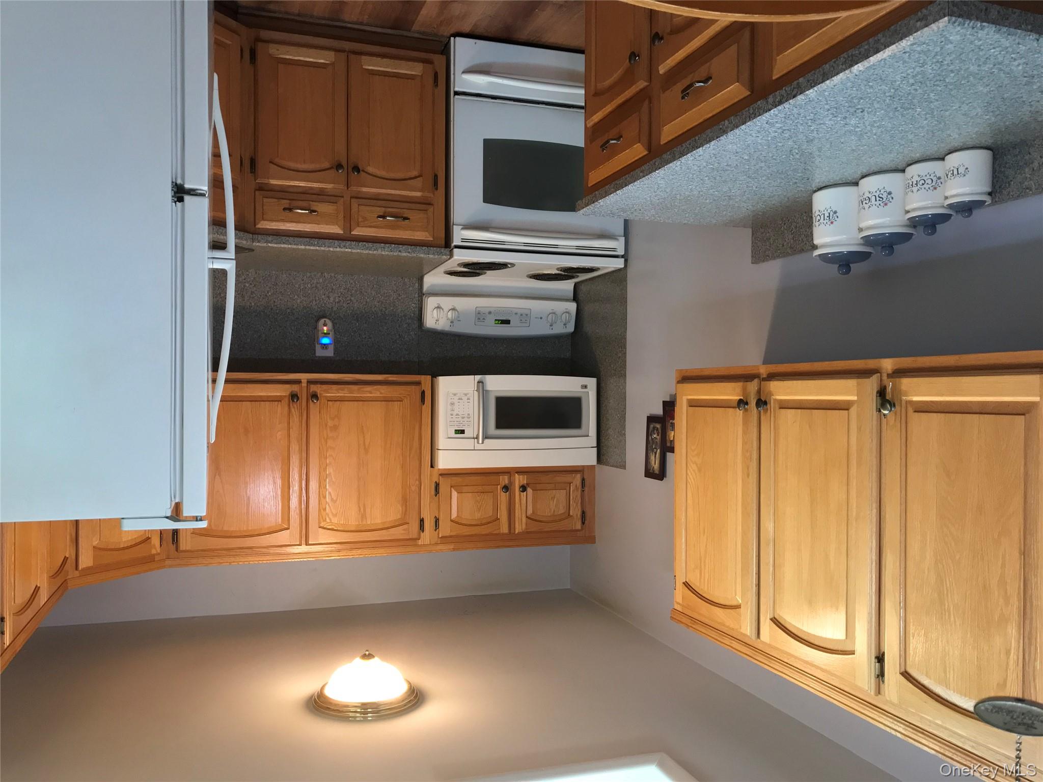 405 Woodbridge Drive, Unit D Ridge, NY 11961 - Photo 4 of 13 a kitchen with stainless steel appliances granite countertop a stove a sink and a microwave