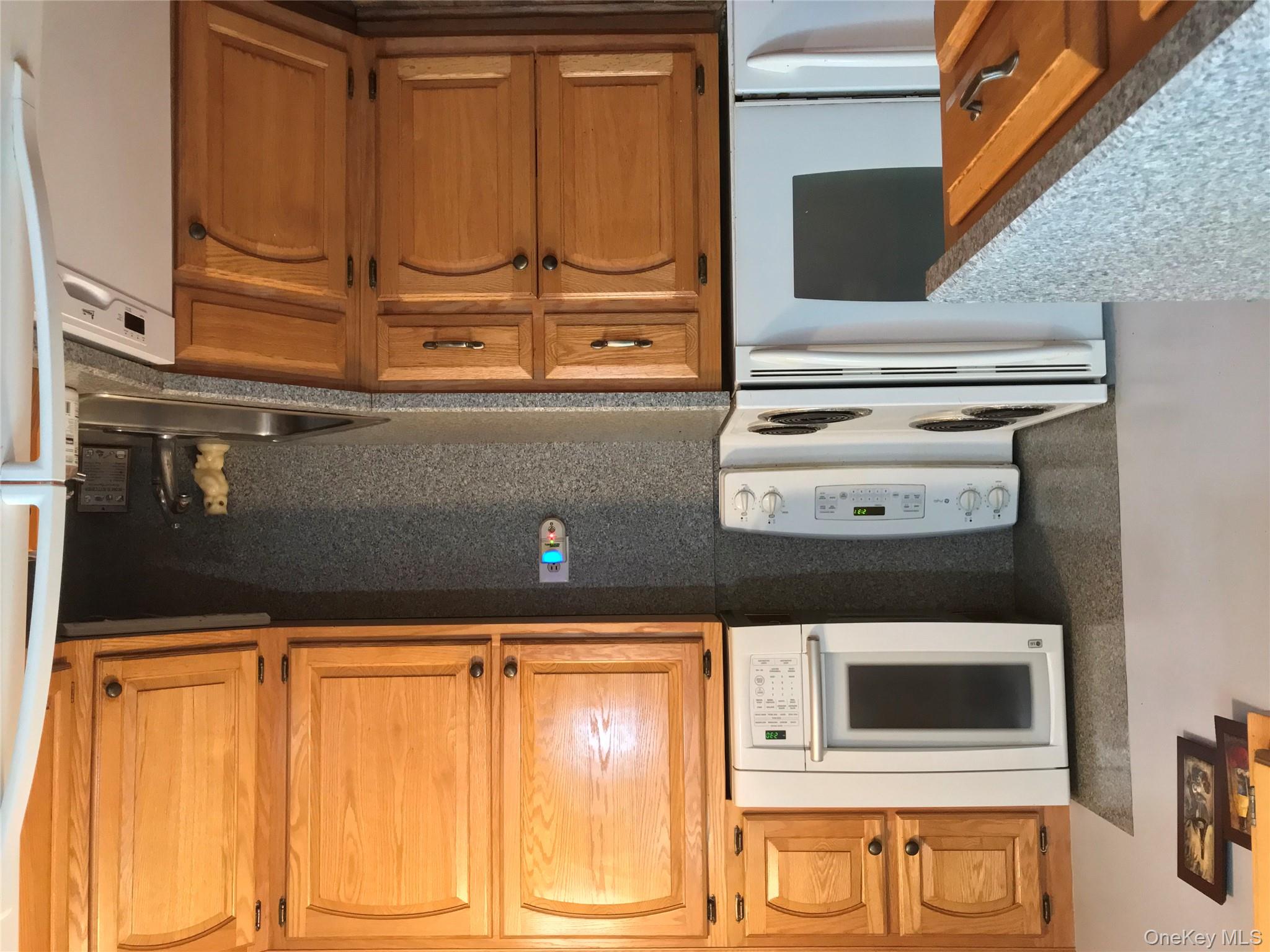 405 Woodbridge Drive, Unit D Ridge, NY 11961 - Photo 5 of 13 a kitchen with granite countertop cabinets stainless steel appliances and a counter space