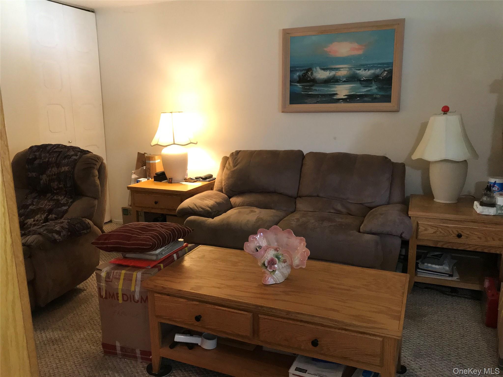 405 Woodbridge Drive, Unit D Ridge, NY 11961 - Photo 6 of 13 a living room with furniture and a lamp