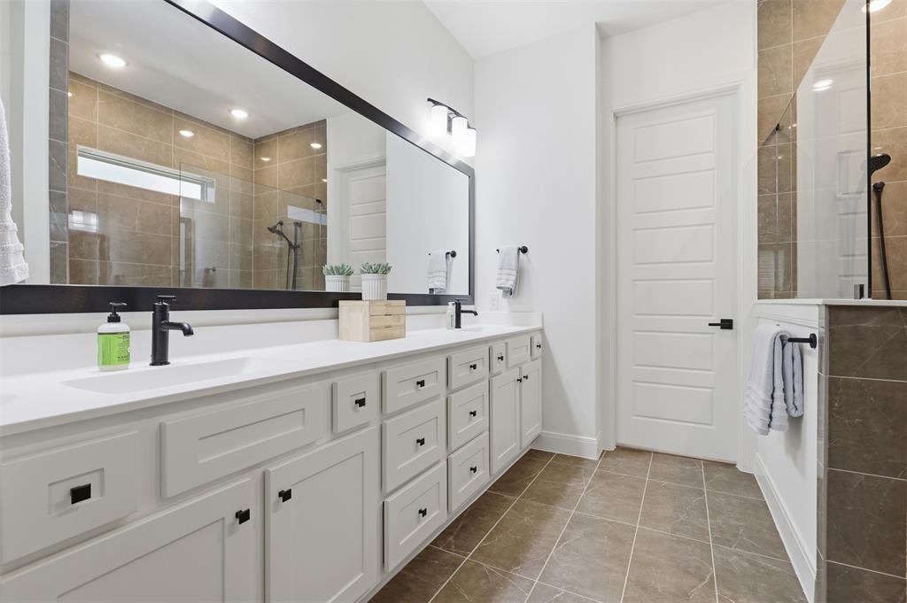 15413 Short Rdg Lane Fort Worth, TX 76008 - Photo 35 of 39 Bathroom featuring a dual vanity with white cabinetry, matte black hardware, and an expansive wall-mounted mirror