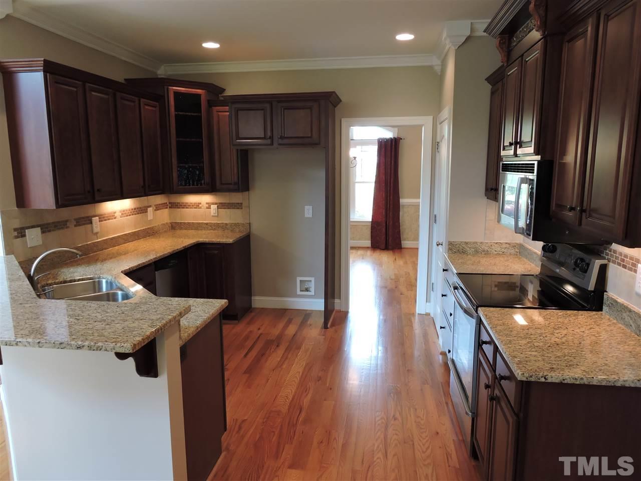 223 Fletcher Ridge Road Timberlake, NC 27583 - Photo 13 of 24 a kitchen with stainless steel appliances granite countertop a sink a stove and a wooden floors