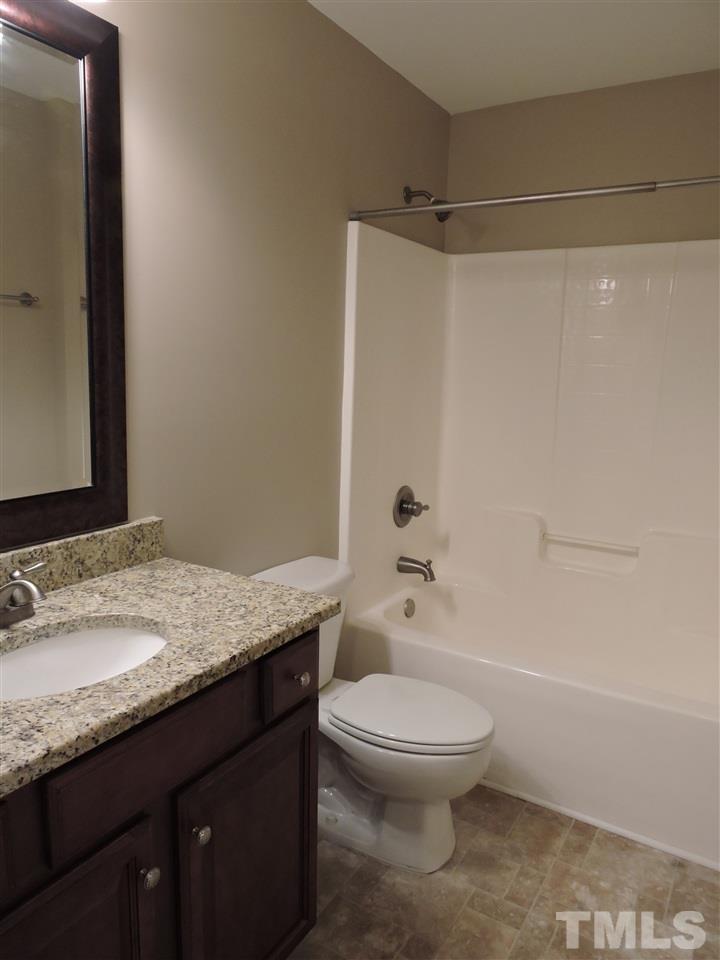 223 Fletcher Ridge Road Timberlake, NC 27583 - Photo 20 of 24 a bathroom with a granite countertop sink a toilet and shower