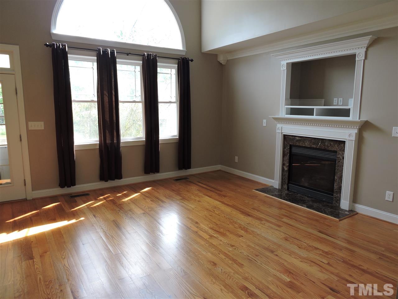 223 Fletcher Ridge Road Timberlake, NC 27583 - Photo 4 of 24 an empty room with wooden floor fireplace and windows