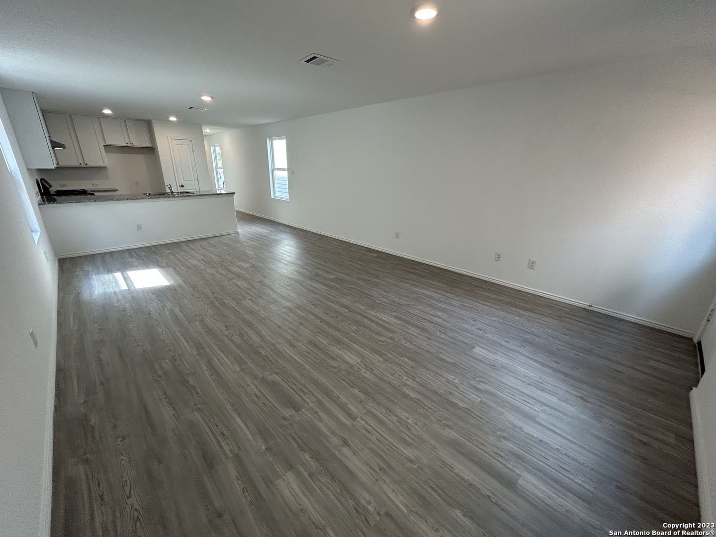 11026 Tree Line San Antonio, TX 78223 - Photo 10 of 31 an empty room with wooden floor and kitchen view