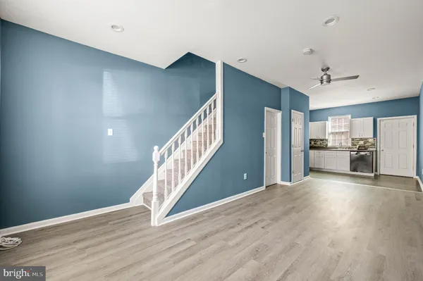 a view of empty room with wooden floor and kitchen view