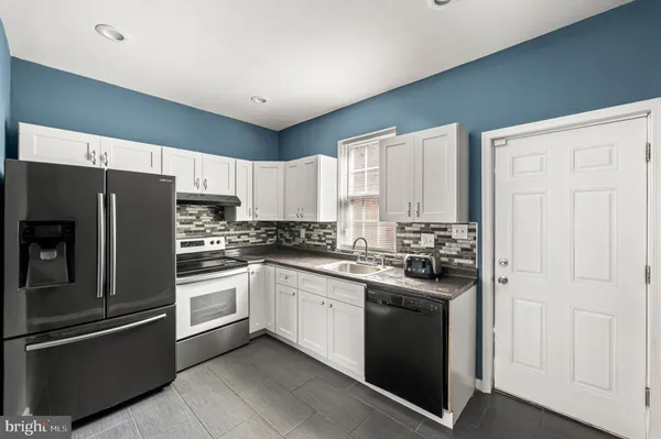 a kitchen with granite countertop a sink a stove and cabinets