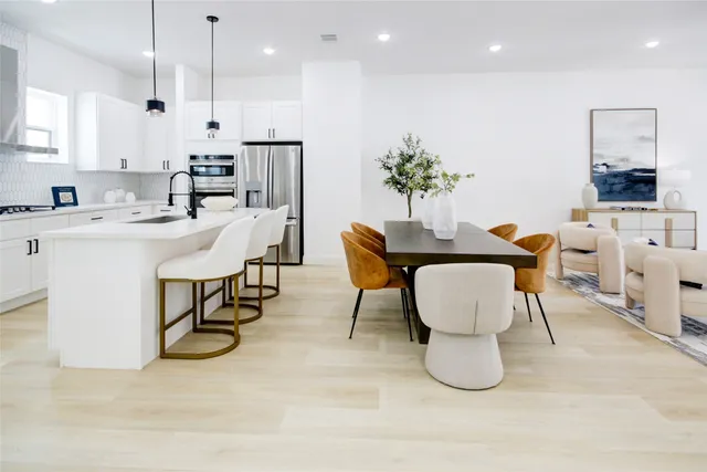 a dining room with furniture a potted plant and kitchen view