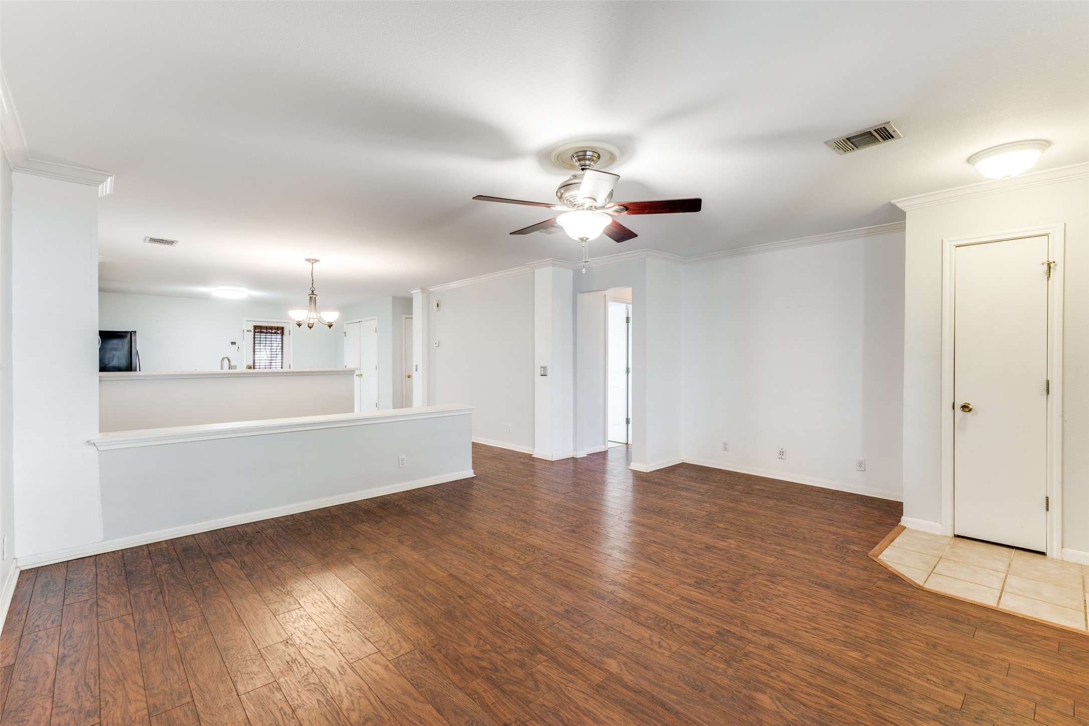 272 Tobin Drive Buda, TX 78610 - Photo 15 of 25 Unfurnished living room with ornamental molding, dark wood-style floors, a ceiling fan, and hanging lights