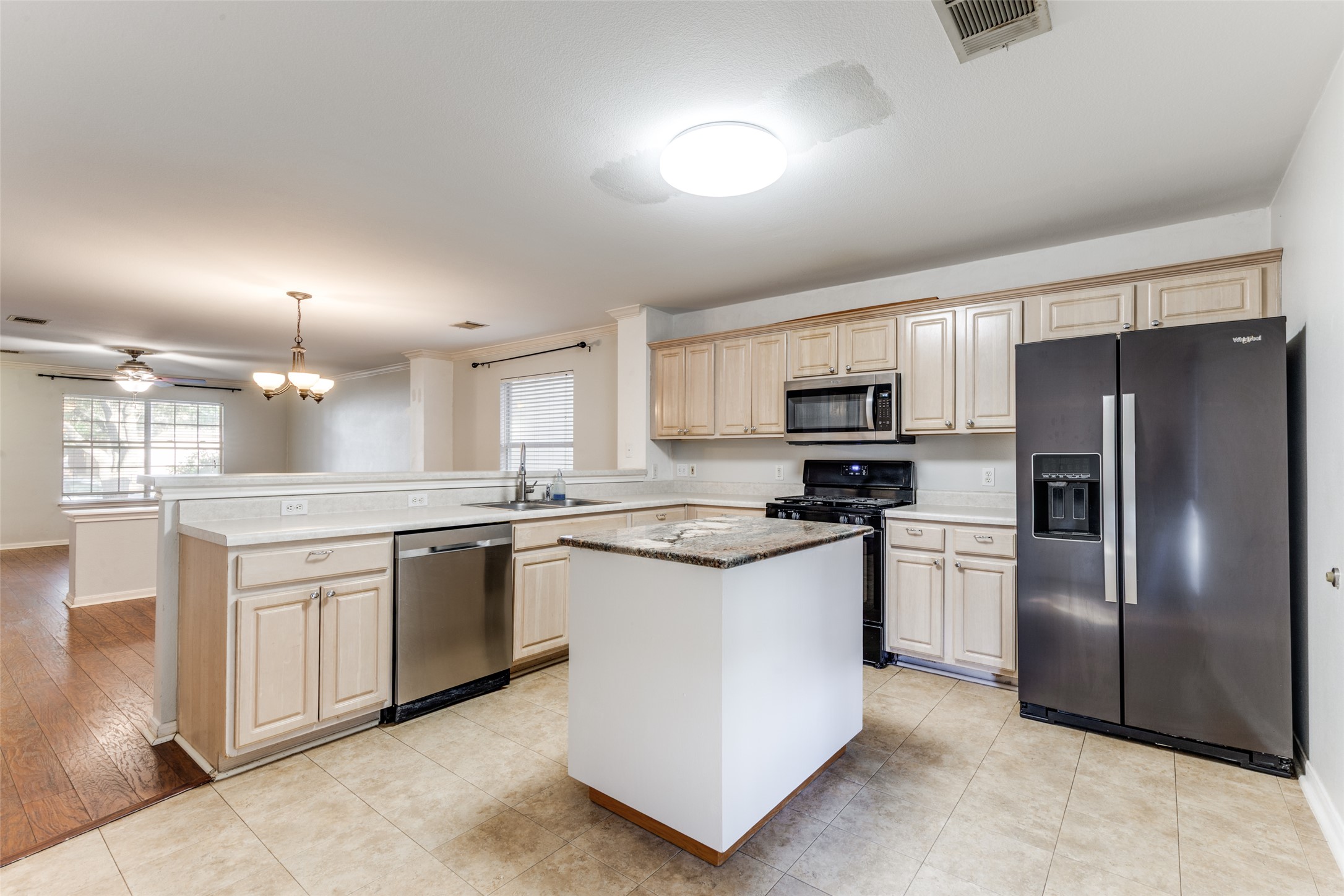 272 Tobin Drive Buda, TX 78610 - Photo 5 of 25 Kitchen with stainless steel appliances, a chandelier, a peninsula, a ceiling fan, and light wood finish cabinets