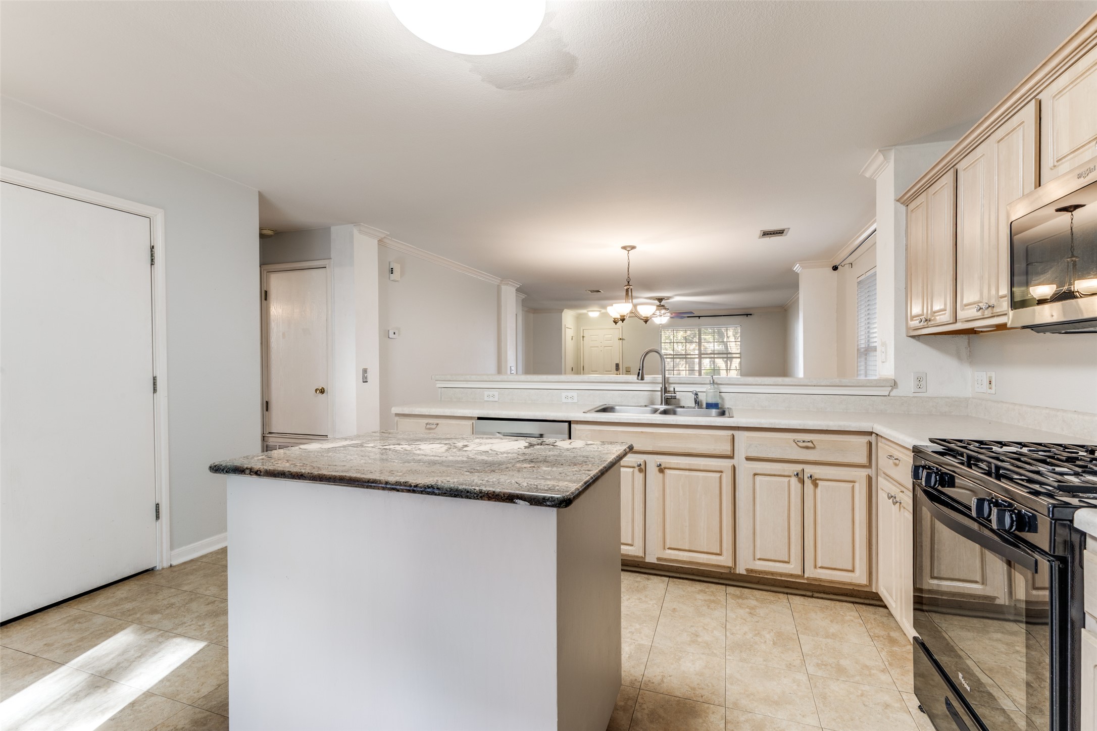 272 Tobin Drive Buda, TX 78610 - Photo 6 of 25 Kitchen featuring hanging lights, stainless steel appliances, a peninsula, light wood finish cabinets, and a center island