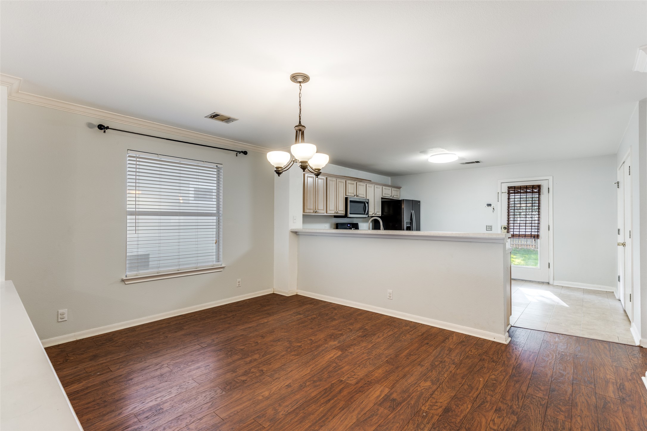 272 Tobin Drive Buda, TX 78610 - Photo 8 of 25 Kitchen featuring dark wood-style floors, a chandelier, light countertops, refrigerator with ice dispenser, and a peninsula