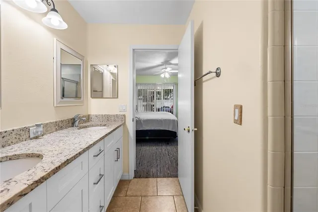a en suite bathroom with a granite countertop sink and a mirror