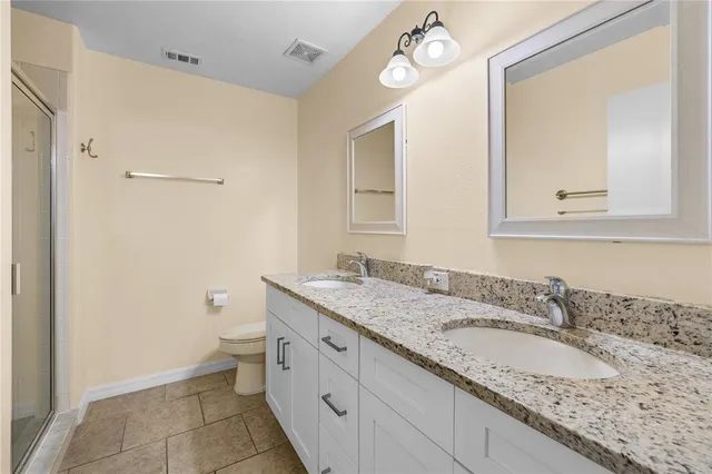 a bathroom with a granite countertop sink toilet and mirror