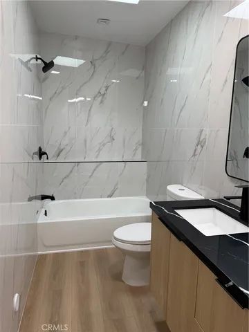 a bathroom with a granite countertop sink a toilet a mirror and bathtub