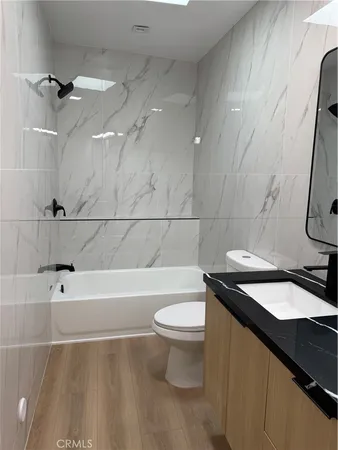 a bathroom with a granite countertop sink a toilet a mirror and bathtub