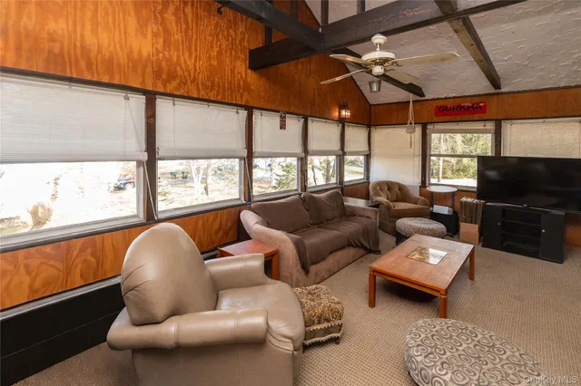 a living room with furniture a ceiling fan and a large window