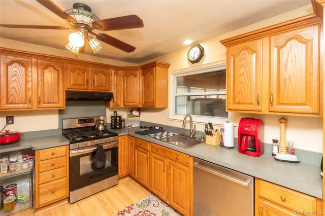 a kitchen with granite countertop a sink stainless steel appliances cabinets and a window