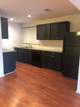 a large kitchen with granite countertop wooden cabinets and a wooden floor