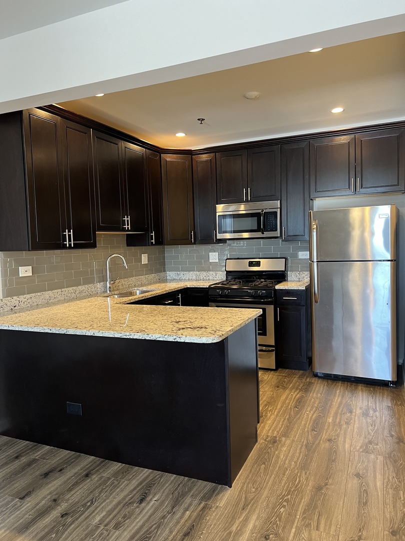 625 Deerfield Road, Unit 402 Deerfield, IL 60015 - Photo 3 of 5 a kitchen with stainless steel appliances granite countertop a refrigerator a sink a stove a microwave and wooden floors